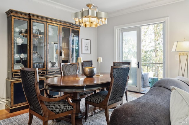 dining area with a notable chandelier, crown molding, light hardwood / wood-style flooring, and french doors