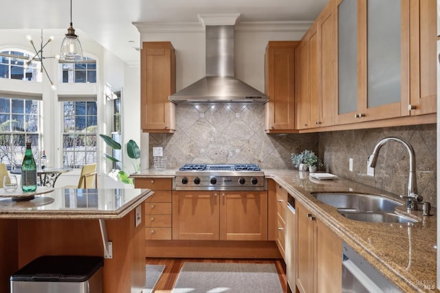 kitchen featuring appliances with stainless steel finishes, tasteful backsplash, sink, wall chimney range hood, and hanging light fixtures