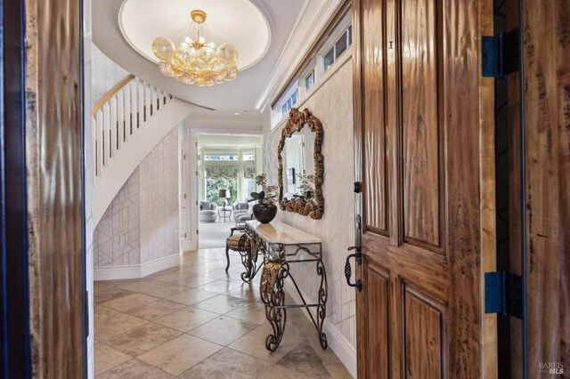 foyer with a tray ceiling, an inviting chandelier, and crown molding