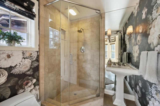 bathroom with toilet, a shower with door, and a wealth of natural light