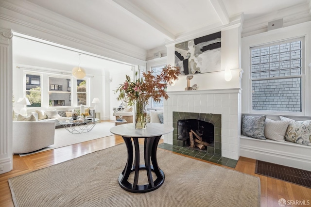 living room with crown molding, hardwood / wood-style floors, a tiled fireplace, and beamed ceiling