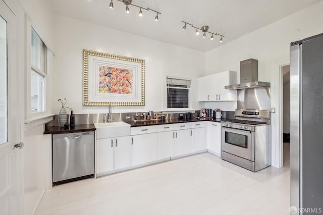 kitchen featuring stainless steel appliances, wall chimney exhaust hood, sink, and white cabinets