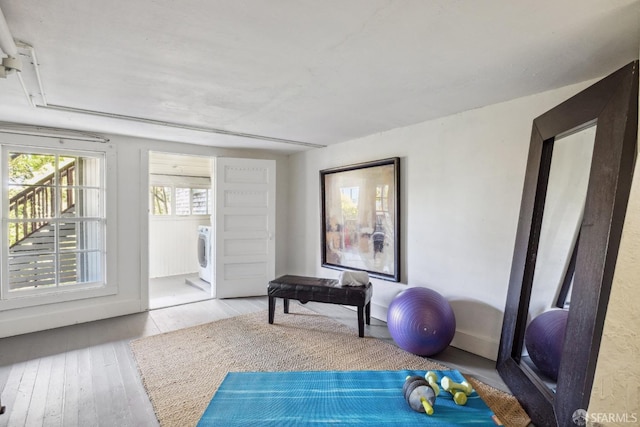 workout area featuring washer / dryer and light wood-type flooring