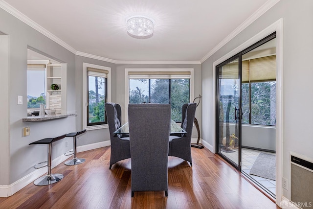 dining room with ornamental molding, hardwood / wood-style flooring, and a healthy amount of sunlight