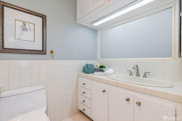 bathroom with tile walls, vanity, and toilet