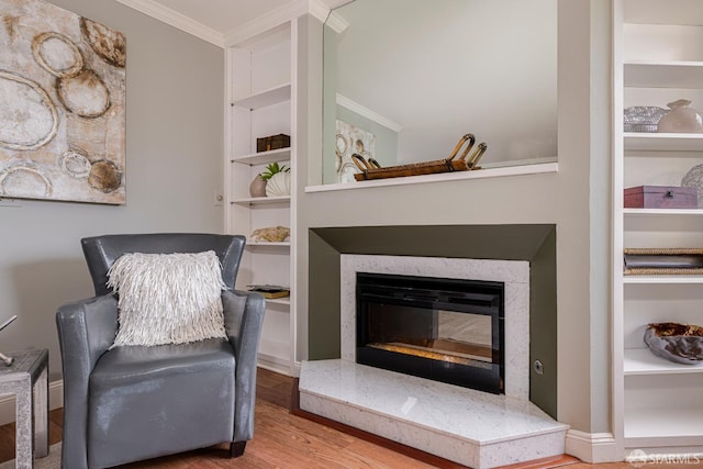 living area featuring ornamental molding, built in features, and hardwood / wood-style floors