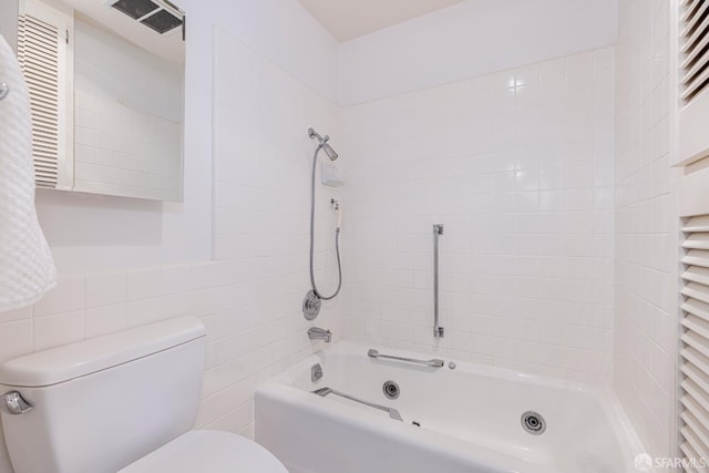 bathroom with tiled shower / bath combo, tile walls, and toilet