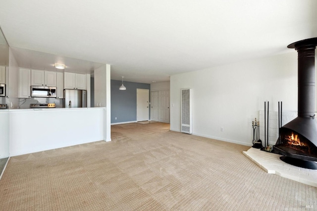 living room featuring light carpet and a wood stove