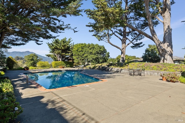 view of swimming pool with a patio and a mountain view