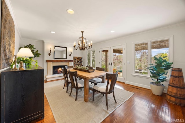 dining space featuring hardwood / wood-style flooring, ornamental molding, a lit fireplace, french doors, and recessed lighting