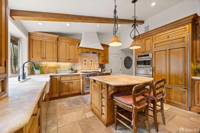 kitchen with stone tile floors, premium range hood, light countertops, appliances with stainless steel finishes, and a center island