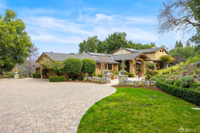 view of front facade featuring a patio, decorative driveway, a front yard, and stucco siding