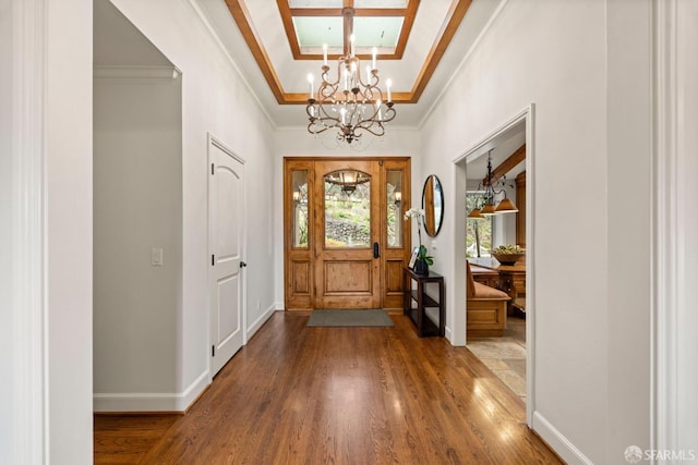 foyer featuring baseboards, ornamental molding, a raised ceiling, and wood finished floors