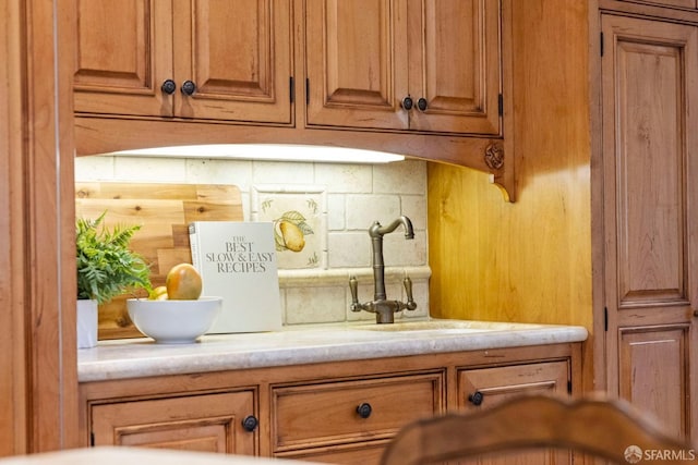 room details featuring brown cabinetry, light countertops, and decorative backsplash