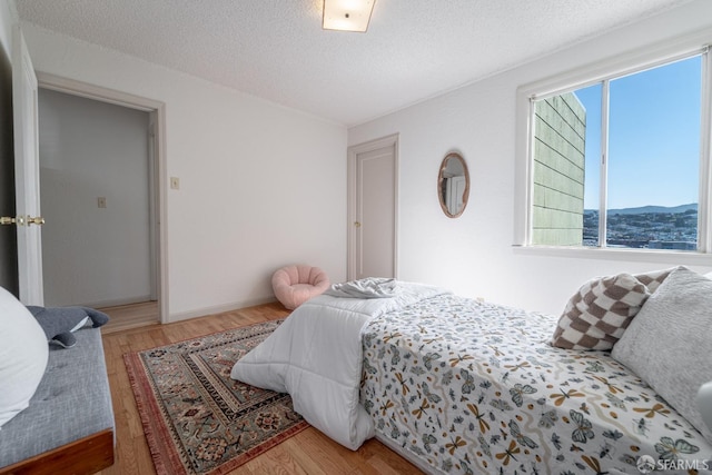 262 Topeka Ave, San Francisco, CA 94124 - bedroom featuring multiple windows, wood finished floors, a textured ceiling, and a mountain view