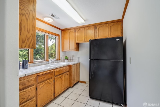 66 Baldwin Ave, Crockett, CA 94525 - kitchen featuring freestanding refrigerator, light tile patterned floors, tile counters, and brown cabinets