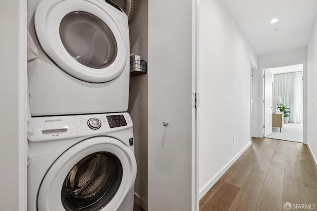 laundry area with stacked washer / drying machine and hardwood / wood-style flooring