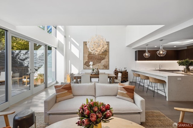 living room with sink, wood-type flooring, french doors, and an inviting chandelier