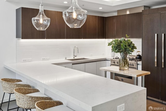 kitchen featuring a kitchen bar, hardwood / wood-style floors, decorative light fixtures, dark brown cabinetry, and sink