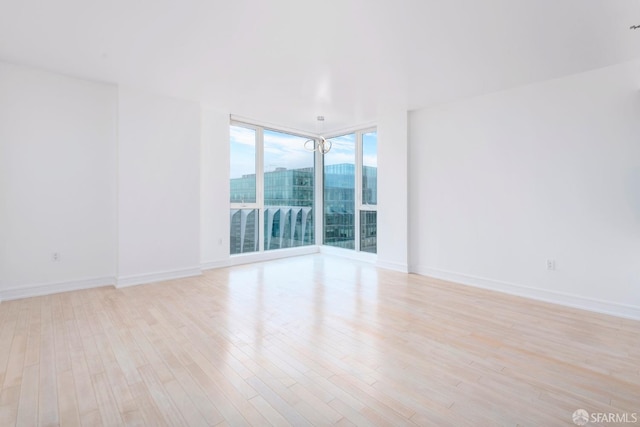 unfurnished room featuring a chandelier and light hardwood / wood-style floors