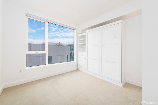 unfurnished bedroom with light carpet and a closet