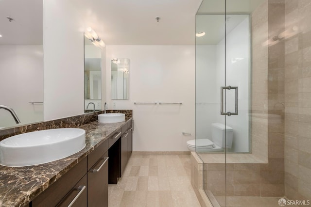 bathroom with vanity, toilet, and a shower with door