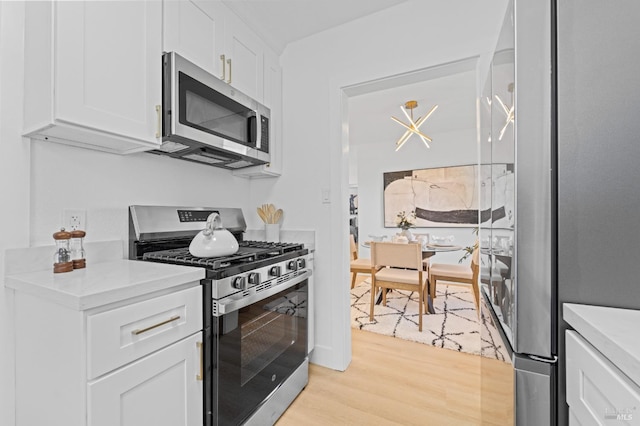 kitchen with stainless steel appliances, light countertops, white cabinets, and light wood-style flooring