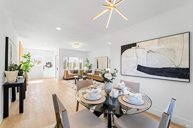 dining room featuring light wood finished floors, baseboards, a notable chandelier, and recessed lighting