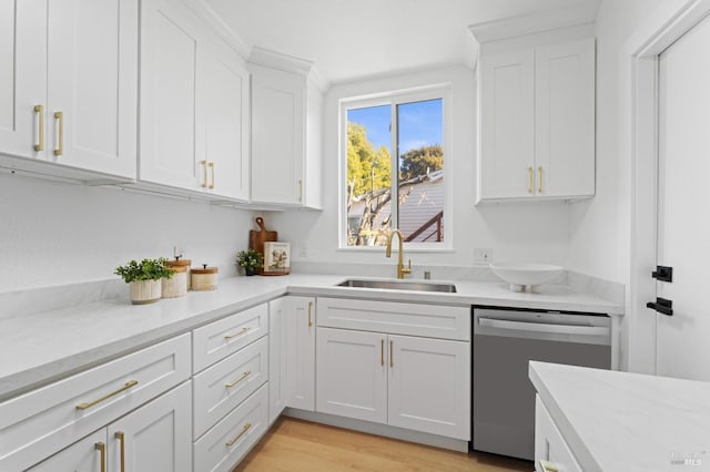 kitchen with light wood finished floors, white cabinets, dishwasher, light stone countertops, and a sink