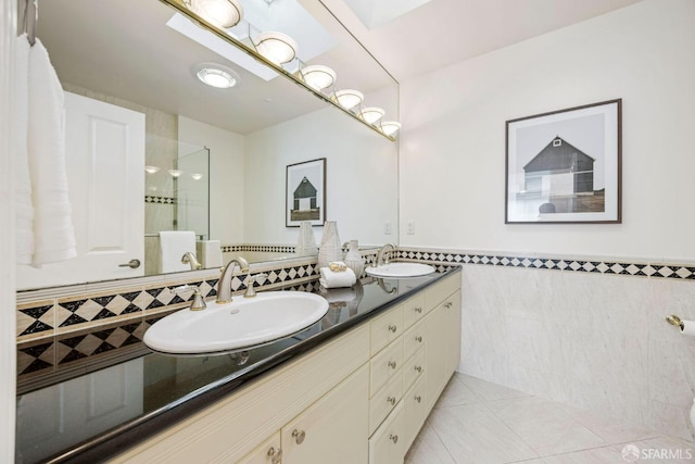 full bath with double vanity, tile patterned flooring, tile walls, and a sink