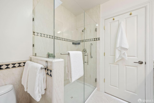 bathroom featuring tile patterned flooring, a shower stall, tile walls, and toilet