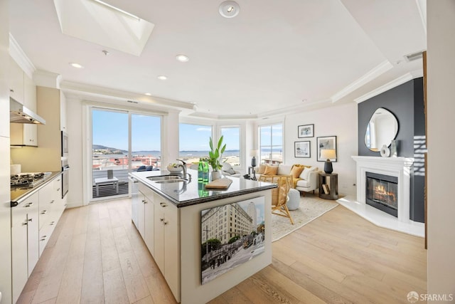 kitchen featuring range hood, stainless steel gas cooktop, a wealth of natural light, ornamental molding, and a sink