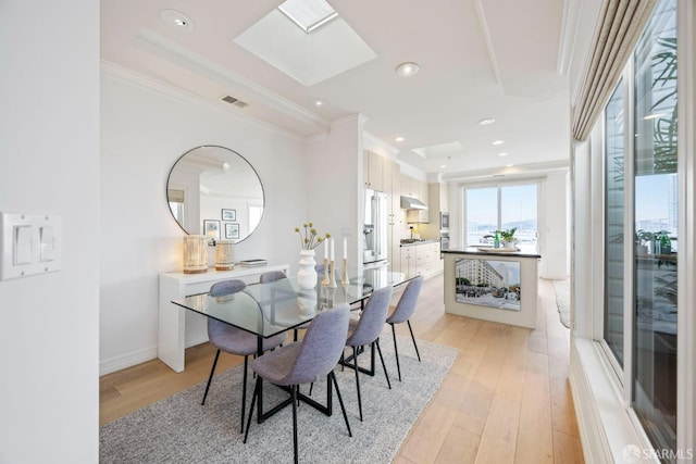 dining area with a skylight, crown molding, recessed lighting, visible vents, and light wood-style floors