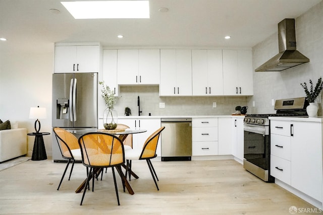 kitchen featuring stainless steel appliances, a sink, wall chimney exhaust hood, and tasteful backsplash