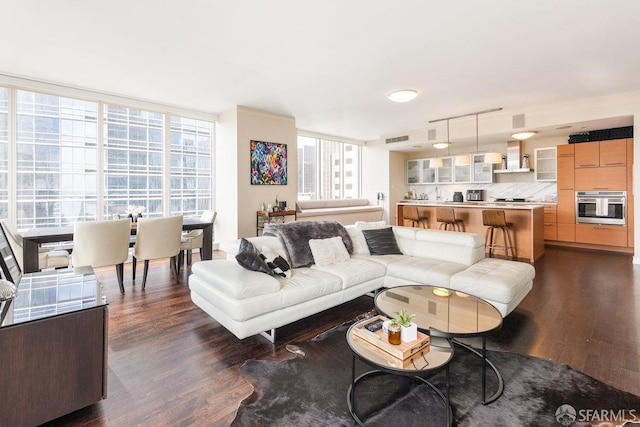 living area featuring a wealth of natural light, floor to ceiling windows, visible vents, and dark wood-style flooring