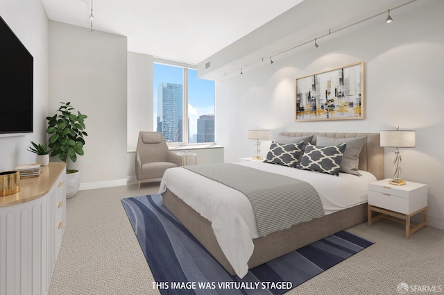 carpeted bedroom featuring rail lighting and baseboards