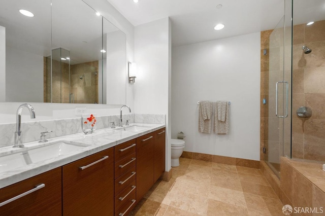 full bath featuring a sink, a shower stall, toilet, and double vanity