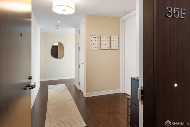 hallway with dark wood-style flooring and baseboards