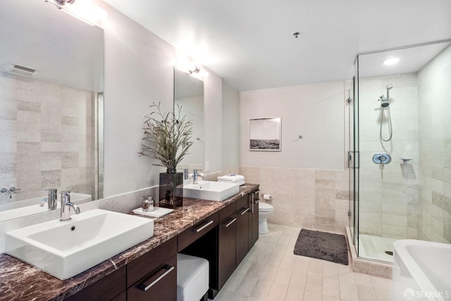 full bathroom with vanity, separate shower and tub, toilet, tile walls, and tile patterned flooring