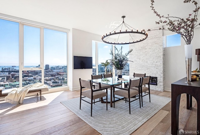 dining space with a stone fireplace, light hardwood / wood-style floors, and a chandelier