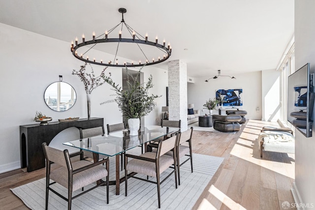 dining space with light hardwood / wood-style flooring, an inviting chandelier, and ornate columns