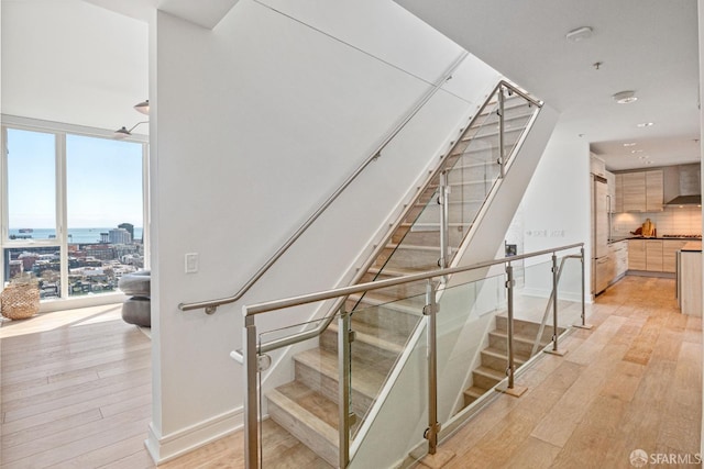 stairs featuring a wall of windows and hardwood / wood-style floors