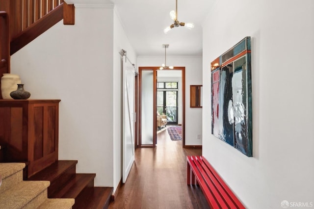 hall with dark hardwood / wood-style flooring, ornamental molding, and a notable chandelier