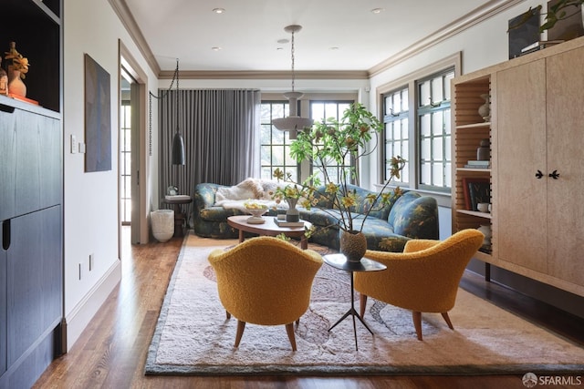 living area with baseboards, wood finished floors, and crown molding