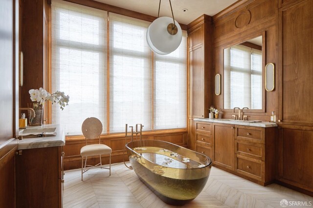 bathroom with a freestanding tub, wood walls, and vanity