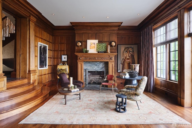 living area with a fireplace, wood finished floors, wooden walls, and crown molding