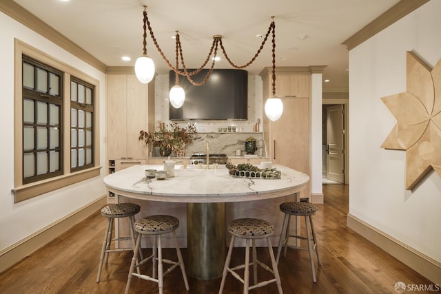 kitchen with a breakfast bar area, tasteful backsplash, an island with sink, and ornamental molding