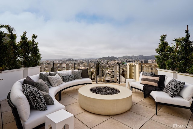 view of patio / terrace with fence, an outdoor living space with a fire pit, and a mountain view