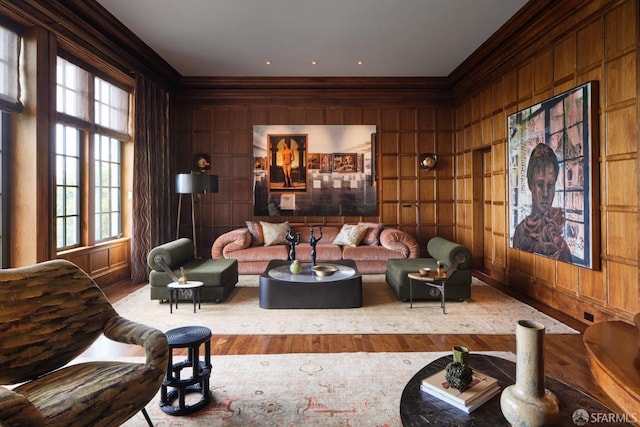 sitting room with wood finished floors, wooden walls, and crown molding