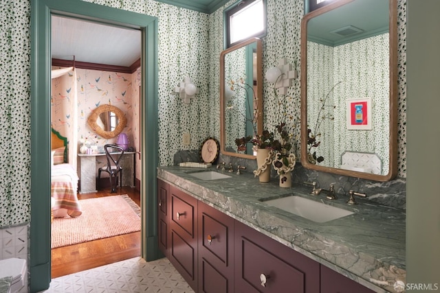 bathroom featuring wallpapered walls, ornamental molding, connected bathroom, and a sink